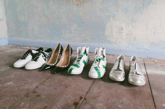 Auf einem alten Holzdielenboden stehen Schuhe aufgereiht.