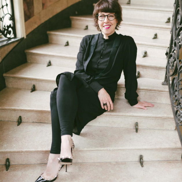 Stilberaterin Caro ganz in schwarz gekleidet sitzt auf einer Treppe.